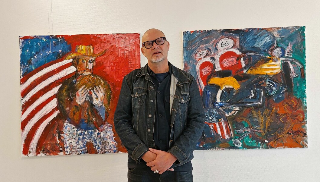 Gunnar Lindberg framför två av sina målningar från bikerkulturen.