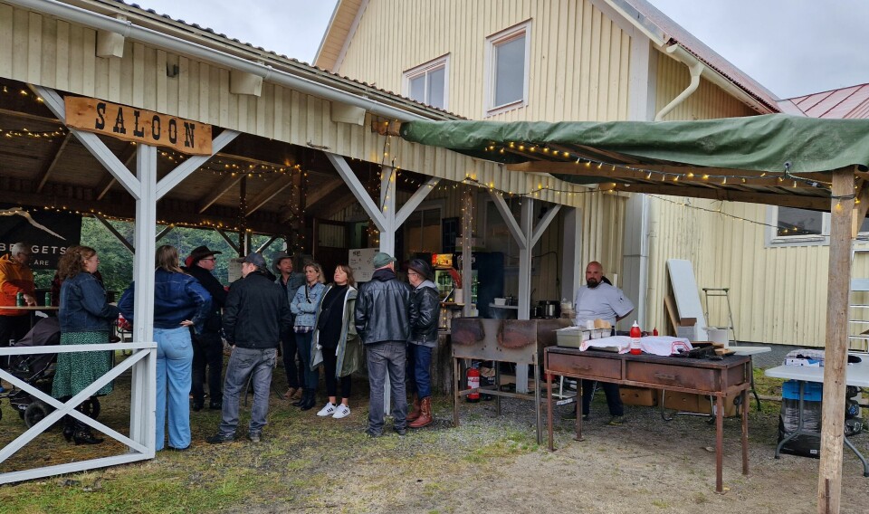 Glada festbesökare samlas under taket i saloonen för att undkomma regnskurarna och fylla på med mat och dryck.